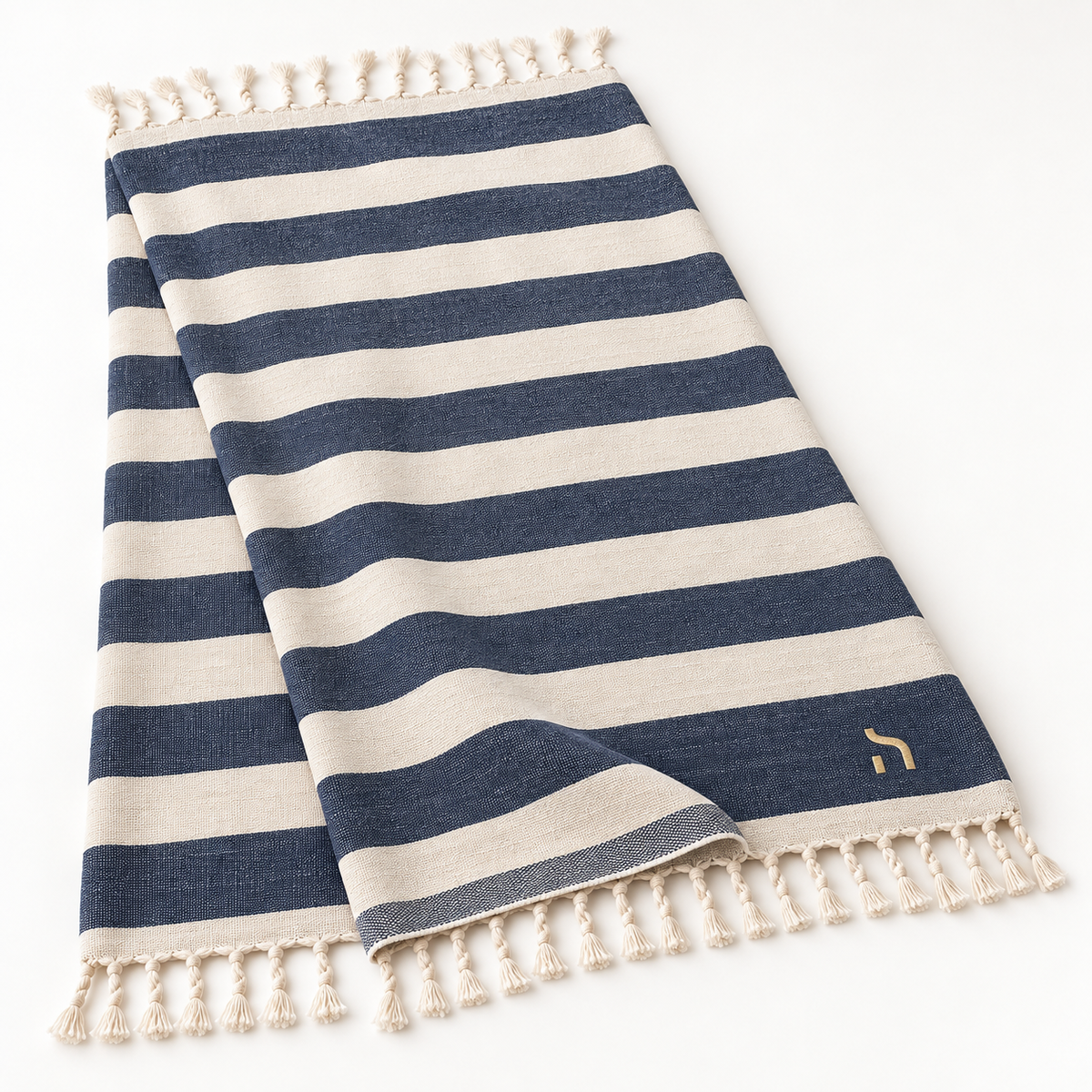 Gestreiftes Haensch Coast Hamam-Strandtuch in Navy und Cream mit handgeknüpften Fransen und goldenem Haensch-Zeichen.