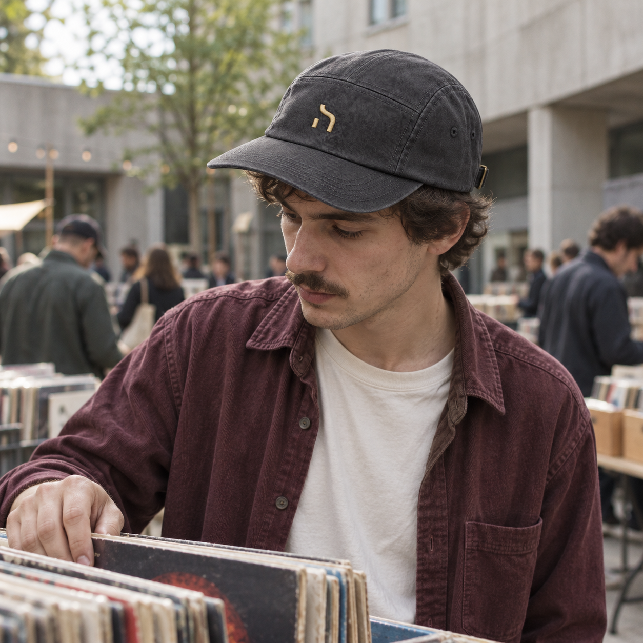 Mann mit graphitgrauer Haensch Utility Cap und goldenem Zeichen sucht auf einem Chemnitzer Markt nach Schallplatten.