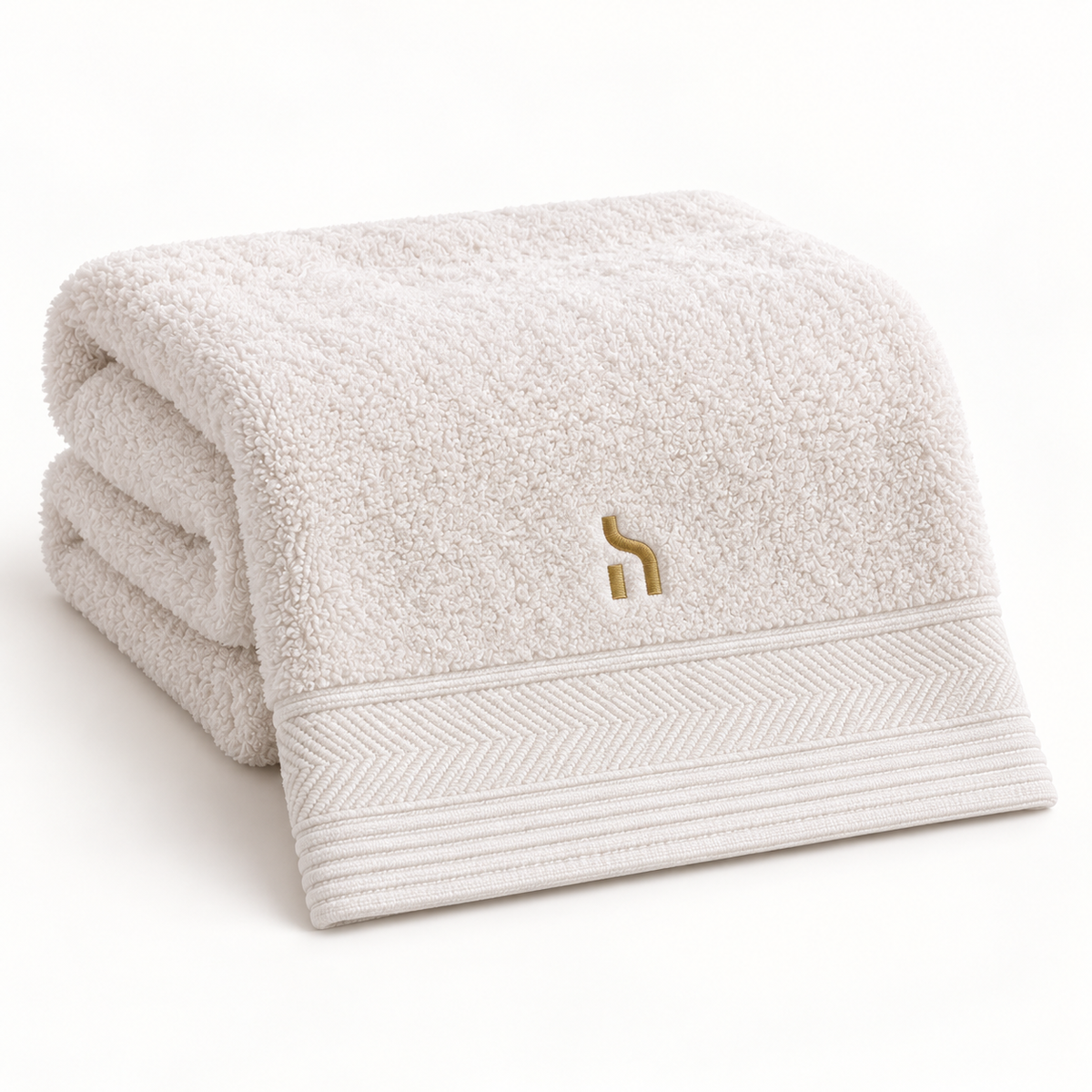 Gefaltetes Ivory-Cream-farbenes Haensch Coast Bamboo Spa Towel mit dekorativem Saum und goldenem Haensch-Zeichen.
