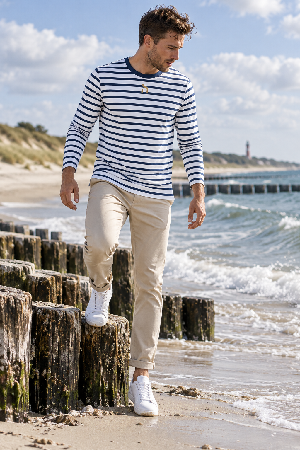 Mann trägt das gestreifte Haensch Coast Longsleeve in White/Navy mit goldenem Haensch-Zeichen am Strand von Swinemuende.