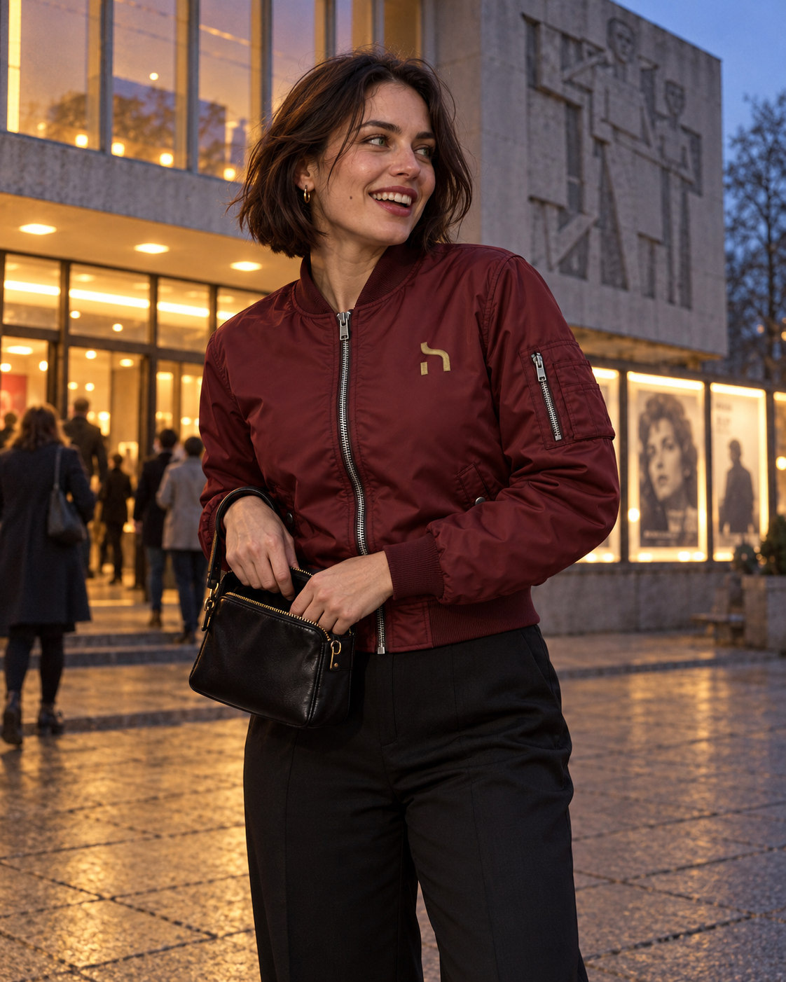 Frau trägt die burgundyfarbene Haensch Studio Bomber Jacket vor moderner Architektur in Berlin.