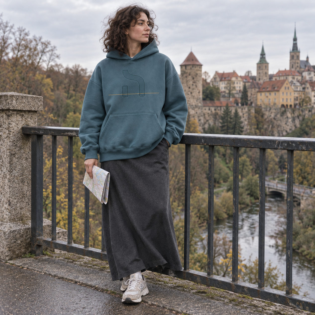 Junge Frau trägt den berylblauen Haensch Studio Box Hoodie an der Friedensbrücke mit Blick auf die Bautzener Altstadt.