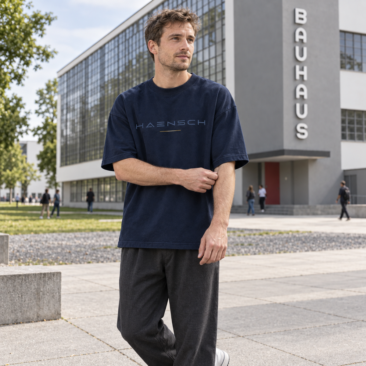 Junger Mann trägt das marineblaue Haensch Studio Oversized Box T‑Shirt vor dem Bauhaus Dessau.