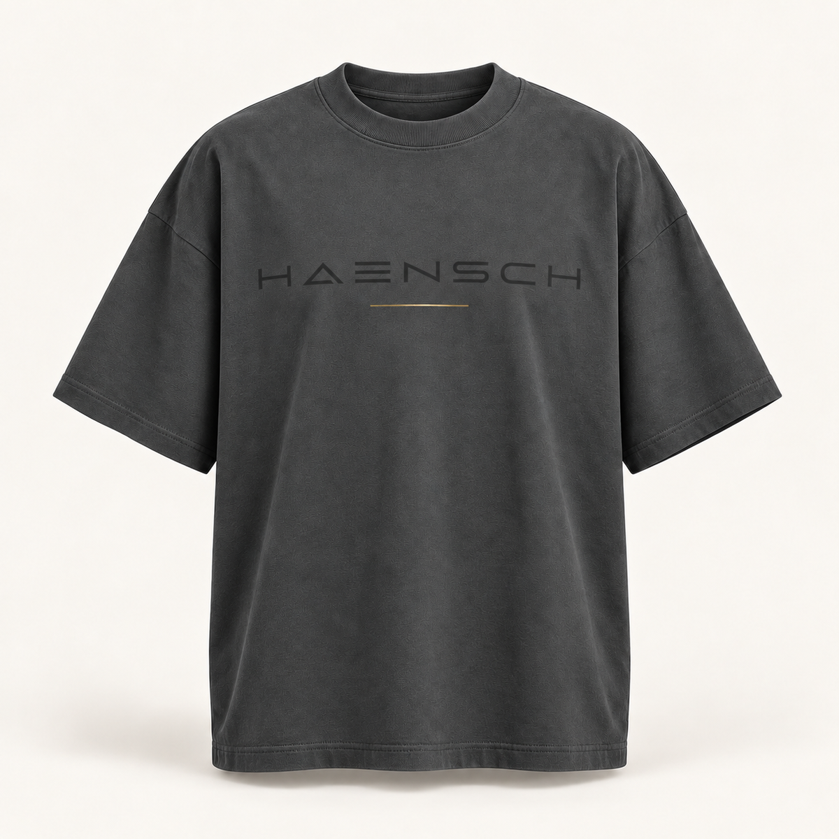 Magnetgraues Haensch Studio Oversized Box T‑Shirt mit dunklem HAENSCH-Schriftzug und feiner goldener Linie in der Vorderansicht.