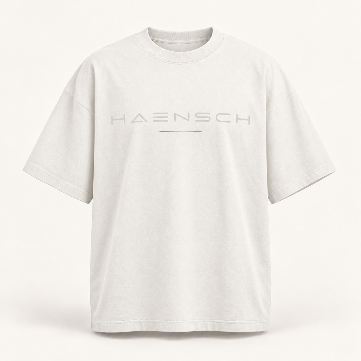 Weißes Haensch Studio Oversized Box T‑Shirt mit hellgrauem HAENSCH-Schriftzug und feiner goldener Linie in der Vorderansicht.