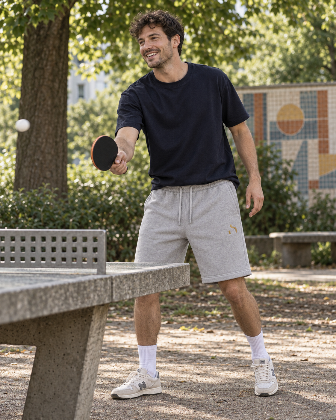 Junger Mann trägt hellgraue Haensch Studio Ultra Heavy Sweatshorts beim Tischtennis in einem Chemnitzer Park.